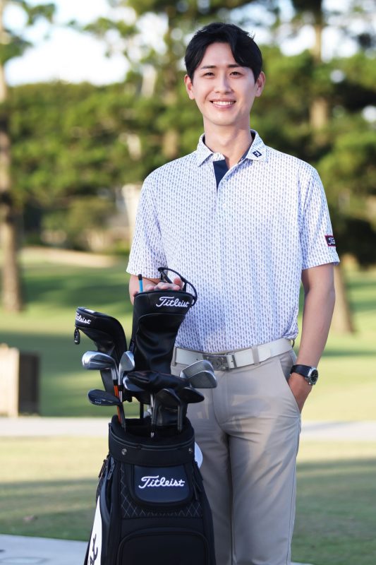Eric Moon smiling beside his golf bag on a course